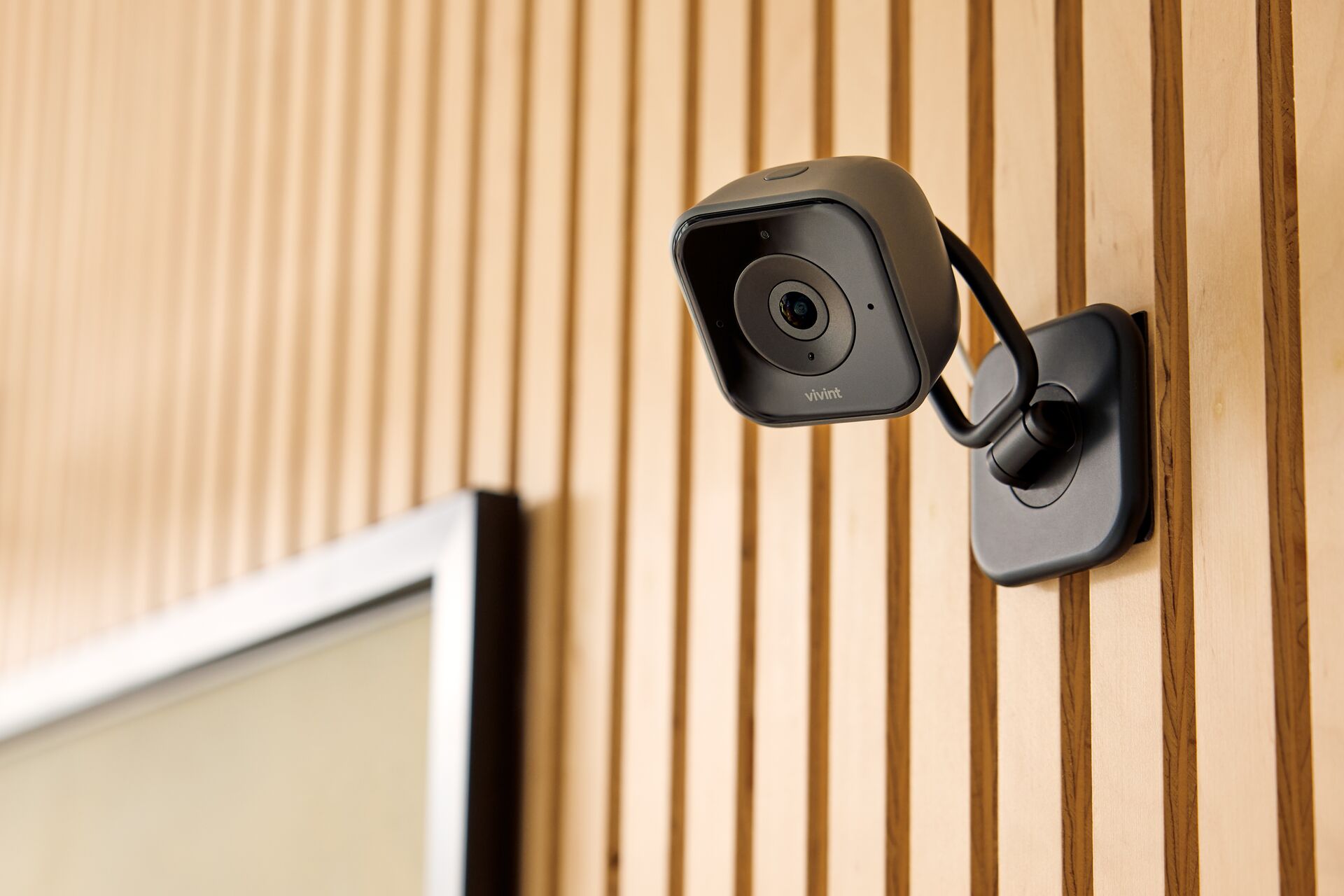 Indoor smart high definition security camera positioned on desktop shelf with wide room coverage